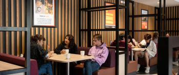 Students sitting in a booth chatting and drinking hot drinks